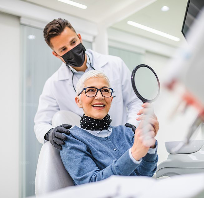 An older woman chatting with her dentist after a dental implant treatment